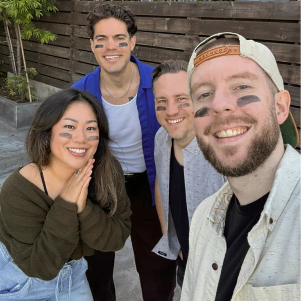 Four Ballpark teammates smiling outdoors with baseball eye black under their eyes