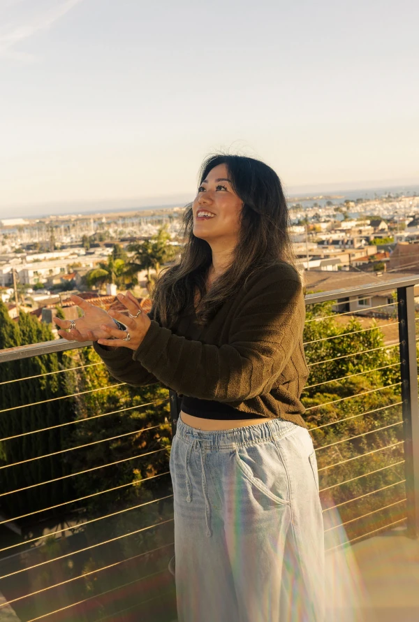 A Ballpark teammate smiling on a balcony overlooking the coastal city at sunset