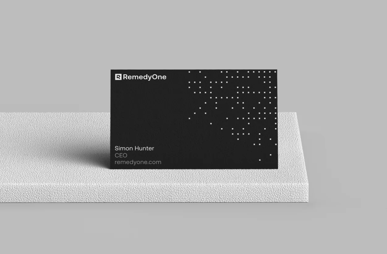 RemedyOne business card mockup — black card with logo, contact details, and generative dot pattern